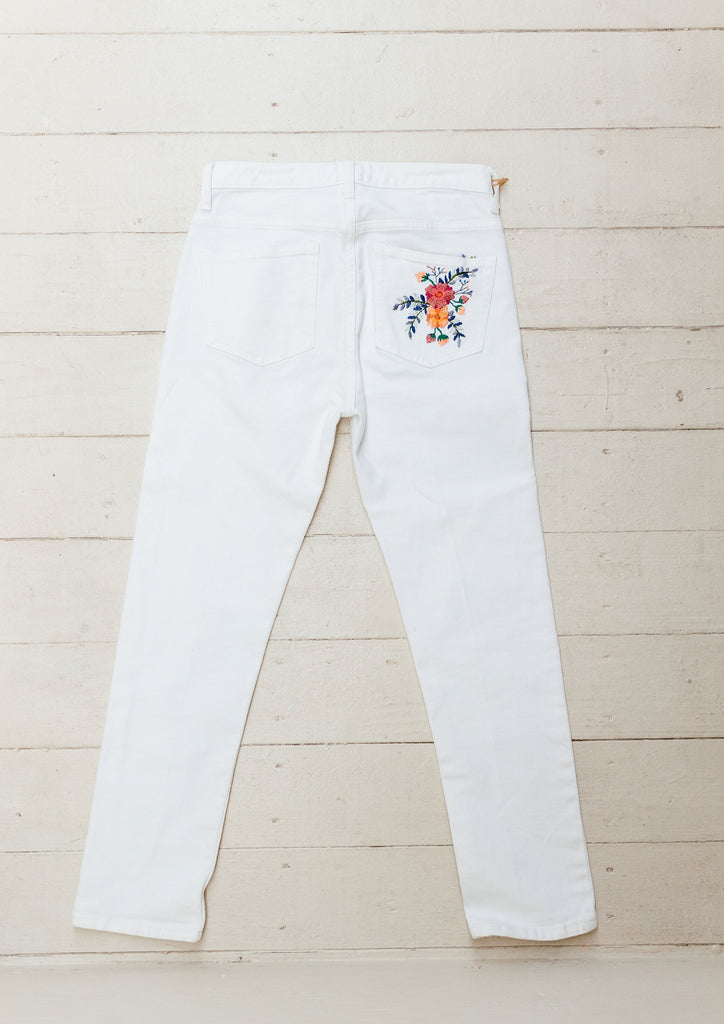 These white jeans are hand-embroidered by a group of talented makers in Guatemala using traditional techniques. The back of the jeans features a colorful embroidered floral design. 