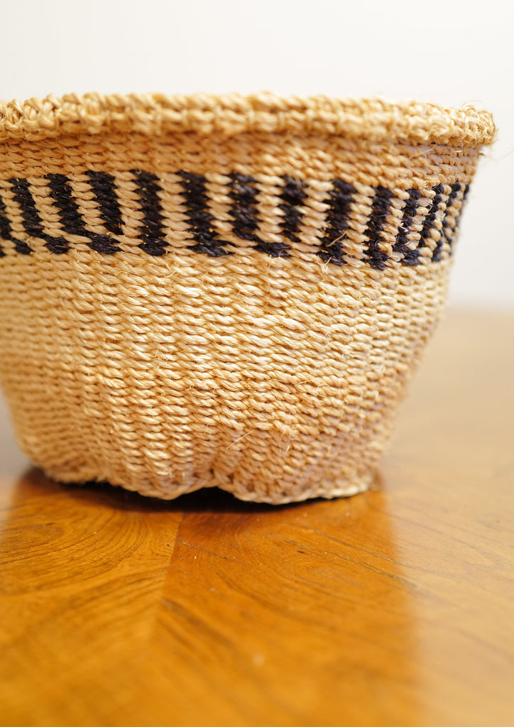 The Mary Mwalugha Basket is handwoven by a weaving group in Kenya. The Mary Mwalugha Basket features a  white and blue horizontal stripe.
