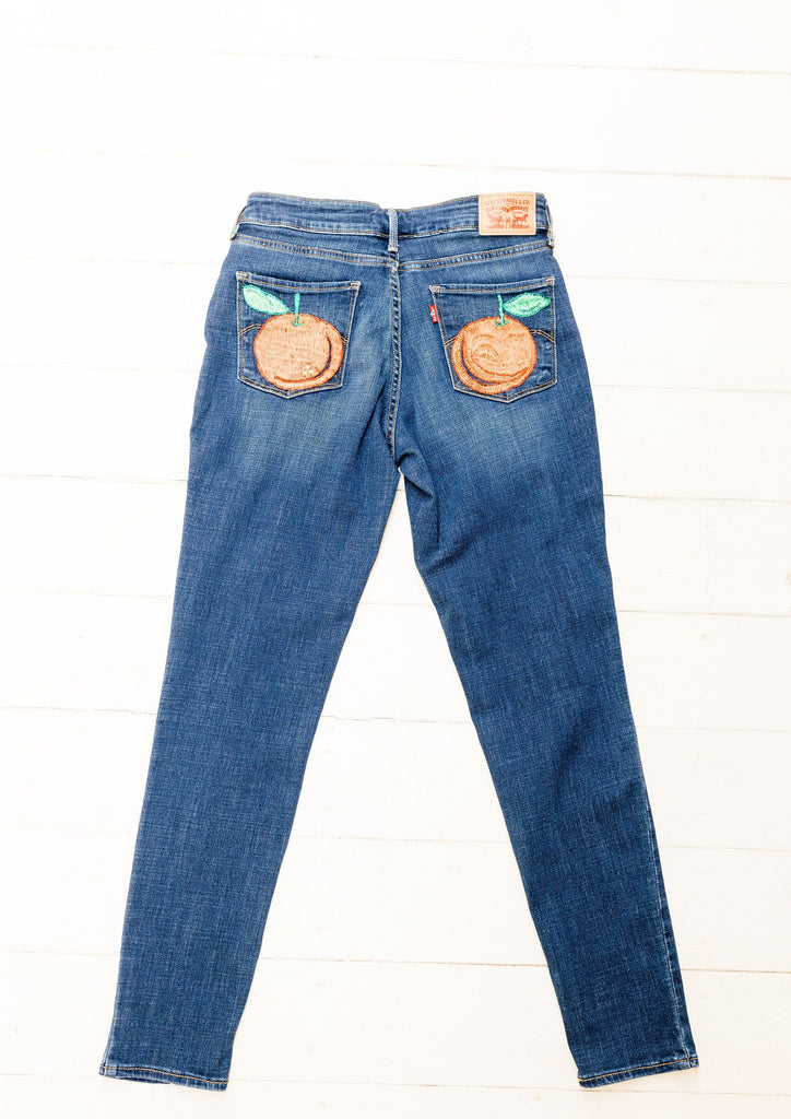 These Levi's jeans are hand-embroidered by a group of talented makers in Guatemala using traditional techniques. The front of the jeans features colorful embroidered lavender and the back pocket juicy oranges. 