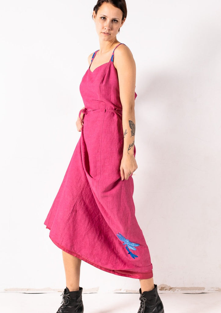 This pink dress is hand-embroidered by a group of talented makers in Guatemala using traditional techniques. The dress features vibrantly colorful embroidered dragonflies on the straps and the skirt.