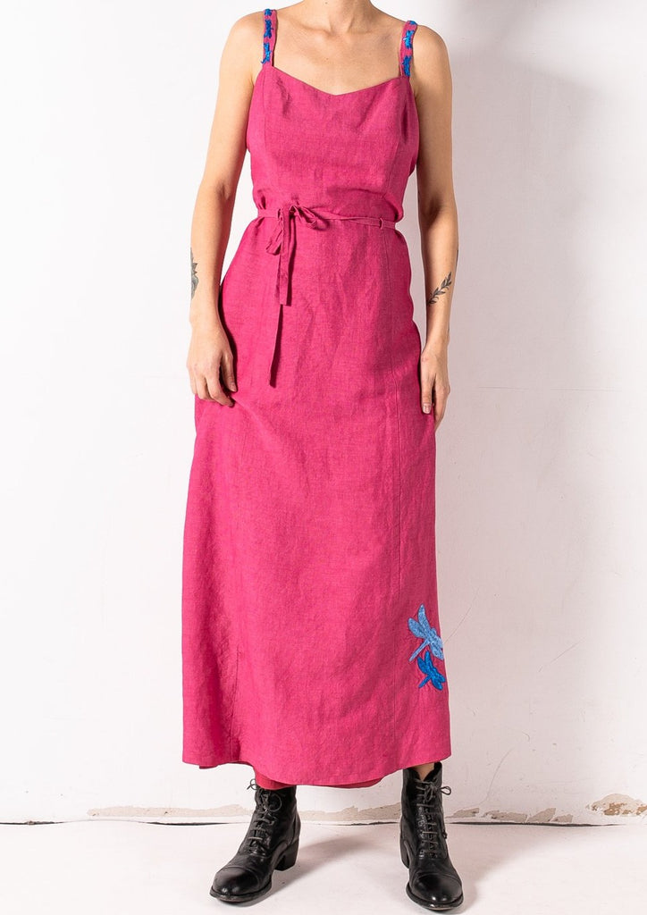 This pink dress is hand-embroidered by a group of talented makers in Guatemala using traditional techniques. The dress features vibrantly colorful embroidered dragonflies on the straps and the skirt.